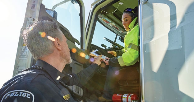 Officer handing documents to driver seated in truck cab