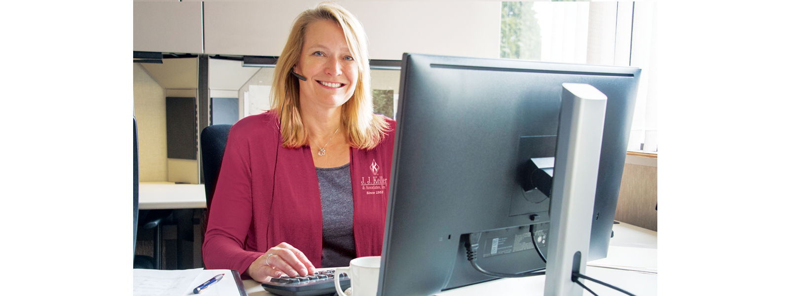 Woman smiling at computer with headset