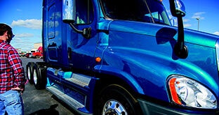 Driver standing by blue semi truck
