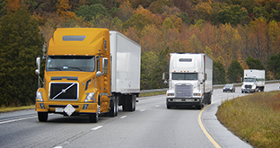 Trucks driving past autumn trees