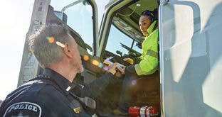 Officer handing documents to driver seated in truck cab