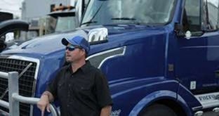 Driver in front of blue semi truck