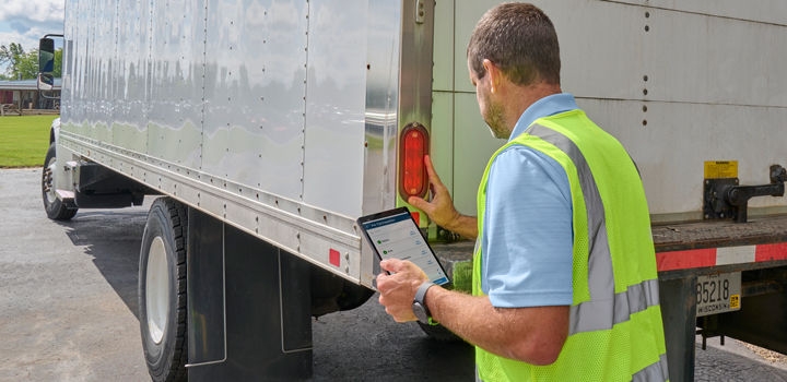 DVIR app on tablet screen, man inspecting box truck