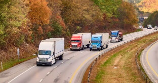 Semi trucks on highway with fall trees