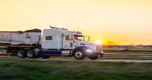 Semi truck driving at sunset