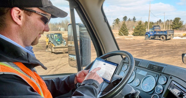 Driver viewing ELD on tablet in cab of truck
